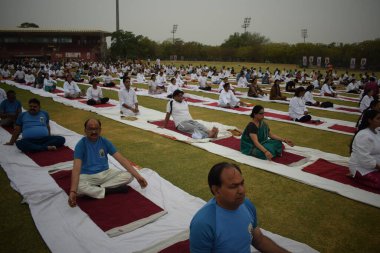 Yeni Delhi, Hindistan, 21 Haziran 2025 - Uluslararası Yoga Günü 'nde Delhi' deki Yamuna Spor Kompleksi 'nde grup Yoga egzersiz oturumu, kriket stadyumunda yoga sınıfına katılan büyük bir grup yetişkin