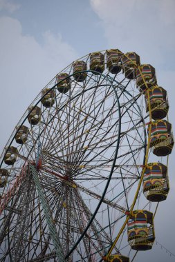 Delhi, Hindistan 'da Dussehra Mela sırasında çok renkli Dev Tekerlek' in yakın çekimi. Dev tekerlek salıncağının alt görüntüsü. Akşam vakti renkli kamaraları olan dönme dolap..