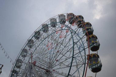 Delhi, Hindistan 'da Dussehra Mela sırasında çok renkli Dev Tekerlek' in yakın çekimi. Dev tekerlek salıncağının alt görüntüsü. Akşam vakti renkli kamaraları olan dönme dolap..