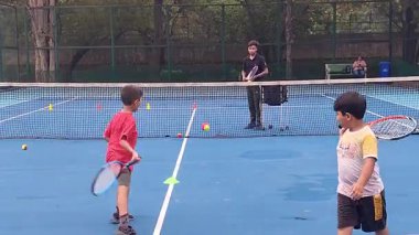 Delhi, Hindistan, 17 Şubat 2025 - Maha Open için kil tenis kortunda antrenörlük yapan genç tenisçiler, yaklaşan turnuva için küçük tenis oyuncuları antrenman yapıyor