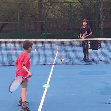 Delhi, Hindistan, 17 Şubat 2025 - Maha Open için kil tenis kortunda antrenörlük yapan genç tenisçiler, yaklaşan turnuva için küçük tenis oyuncuları antrenman yapıyor