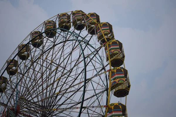 Delhi, Hindistan 'da Dussehra Mela sırasında çok renkli Dev Tekerlek' in yakın çekimi. Dev tekerlek salıncağının alt görüntüsü. Akşam vakti renkli kamaraları olan dönme dolap..