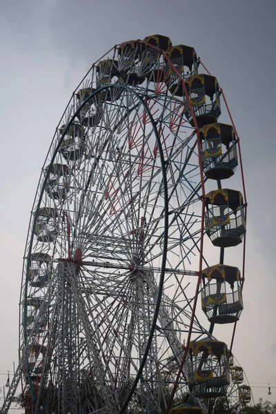 Delhi, Hindistan 'da Dussehra Mela sırasında çok renkli Dev Tekerlek' in yakın çekimi. Dev tekerlek salıncağının alt görüntüsü. Akşam vakti renkli kamaraları olan dönme dolap..