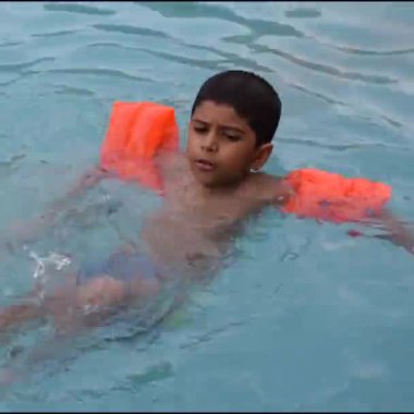 Havuzda yüzen mutlu Hintli çocuk, sıcak yaz tatillerinde hava tüpüyle birlikte yüzen çocuk, büyük bir havuzda yüzen çocuk..