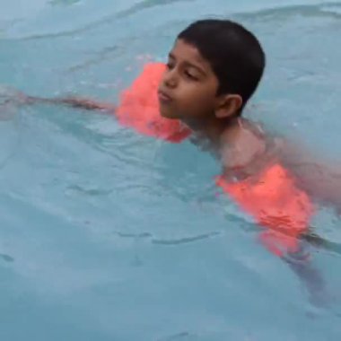 Havuzda yüzen mutlu Hintli çocuk, sıcak yaz tatillerinde hava tüpüyle birlikte yüzen çocuk, büyük bir havuzda yüzen çocuk..