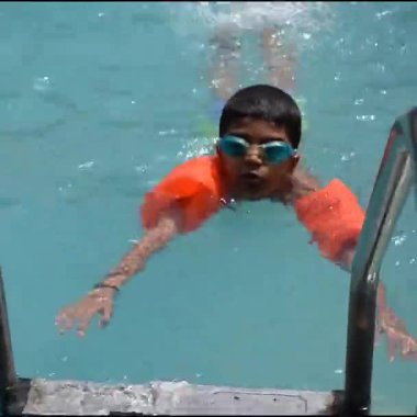 Havuzda yüzen mutlu Hintli çocuk, sıcak yaz tatillerinde hava tüpüyle birlikte yüzen çocuk, büyük bir havuzda yüzen çocuk..