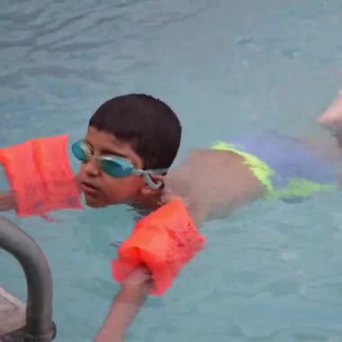 Havuzda yüzen mutlu Hintli çocuk, sıcak yaz tatillerinde hava tüpüyle birlikte yüzen çocuk, büyük bir havuzda yüzen çocuk..