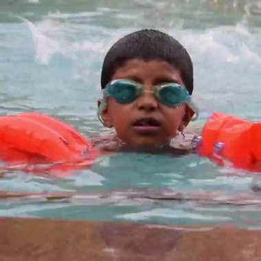 Havuzda yüzen mutlu Hintli çocuk, sıcak yaz tatillerinde hava tüpüyle birlikte yüzen çocuk, büyük bir havuzda yüzen çocuk..