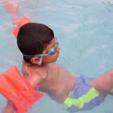 Havuzda yüzen mutlu Hintli çocuk, sıcak yaz tatillerinde hava tüpüyle birlikte yüzen çocuk, büyük bir havuzda yüzen çocuk..