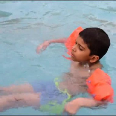 Havuzda yüzen mutlu Hintli çocuk, sıcak yaz tatillerinde hava tüpüyle birlikte yüzen çocuk, büyük bir havuzda yüzen çocuk..