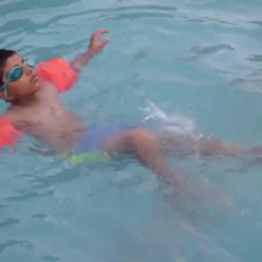 Havuzda yüzen mutlu Hintli çocuk, sıcak yaz tatillerinde hava tüpüyle birlikte yüzen çocuk, büyük bir havuzda yüzen çocuk..