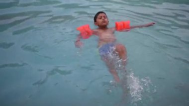 Havuzda yüzen mutlu Hintli çocuk, sıcak yaz tatillerinde hava tüpüyle birlikte yüzen çocuk, büyük bir havuzda yüzen çocuk..