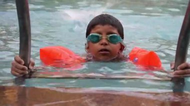 Havuzda yüzen mutlu Hintli çocuk, sıcak yaz tatillerinde hava tüpüyle birlikte yüzen çocuk, büyük bir havuzda yüzen çocuk..