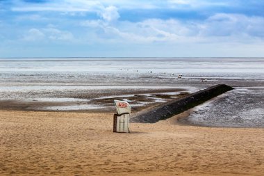 Almanya 'nın Cuxhaven kentindeki Kuzey Denizi' ndeki kumsal. Arka plan beyaz bulutlu mavi bir gökyüzü..