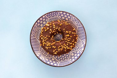 Süslerle süslenmiş güzel bir kaseye yerleştirilmiş fındıklı çikolatalı çörek. Mavi arkaplan.