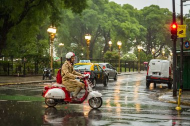 Yağmurlu bir günde Buenos Aires, Arjantin 'deki Recoleta Mahallesi' nde arabaların arasından geçen bir motosikletli..