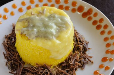 Mısır kuskusu, parçalanmış güneş eti ve beyaz tabakta erimiş peynir. Kuzeydoğu Brezilya mutfağı.