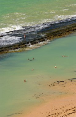 11 Nisan 2005 'te Praia de Boa Viagem, Recife, Pernambuco, Brezilya' da suda ve kumda yaşayan insanlar ve arka planda resifler vardı..
