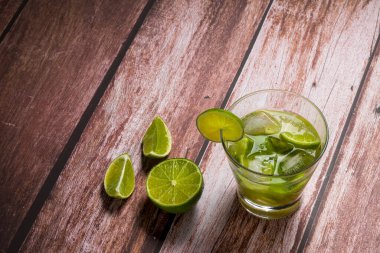 Eski ahşap bir masada limonlu bir bardak caipirinha. Tipik Brezilya içeceği cachaca, limon, buz ve şekerden yapılır..