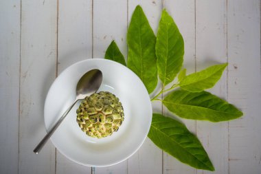 Beyaz bir tabakta, paslanmaz çelik kaşıkla elma şekeri, yıllanmış beyaz bir tahta masada yenmeye hazır. Üst görünüm.