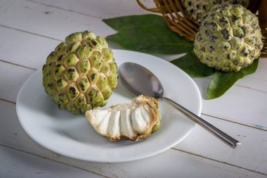 Beyaz bir tabakta, paslanmaz çelik kaşıkla elma şekeri, yıllanmış beyaz bir tahta masada yenmeye hazır..
