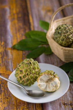 Beyaz tepside, paslanmaz çelik kaşıkla yenmeye hazır elma şekeri. Diğer elma şekerlerine ek olarak eski sarı ahşap bir masada bulanık bir arka planda bir sepet içinde.