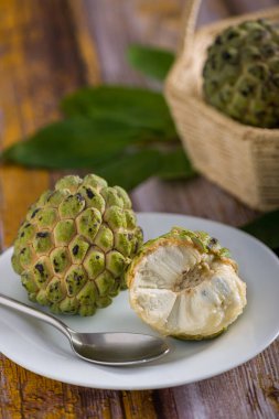 Beyaz tepside, paslanmaz çelik kaşıkla yenmeye hazır elma şekeri. Diğer elma şekerlerine ek olarak eski sarı ahşap bir masada bulanık bir arka planda bir sepet içinde.
