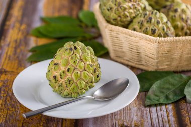 Beyaz tepside, paslanmaz çelik kaşıkla yenmeye hazır elma şekeri. Diğer elma şekerlerine ek olarak eski sarı ahşap bir masada bulanık bir arka planda bir sepet içinde.