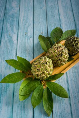 Mavi ahşap masada yaprakları olan üç elma şekeri..