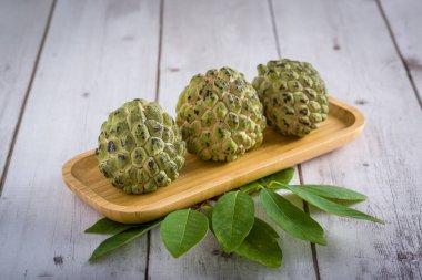 Tahta masada yaprakları olan üç elma şekeri..