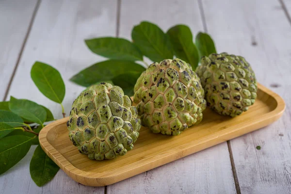 Three sugar apple with leaves on wooden table.