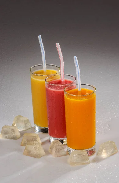 Tre Glas Fruktjuice Med Plastsugrör Och Grå Lutning Bakgrund — Stockfoto