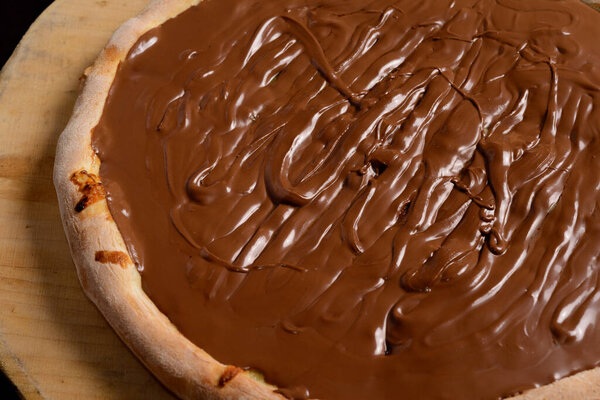 Chocolate pizza on wooden board. Brazilian sweet pizza.