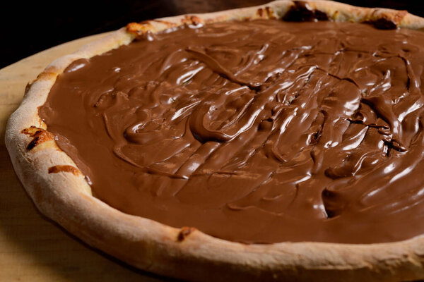 Chocolate pizza on wooden board. Brazilian sweet pizza.