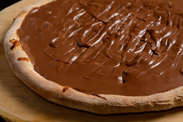 Chocolate pizza on wooden board. Brazilian sweet pizza.
