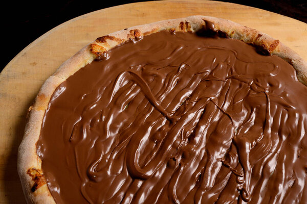 Chocolate pizza on wooden board. Brazilian sweet pizza.