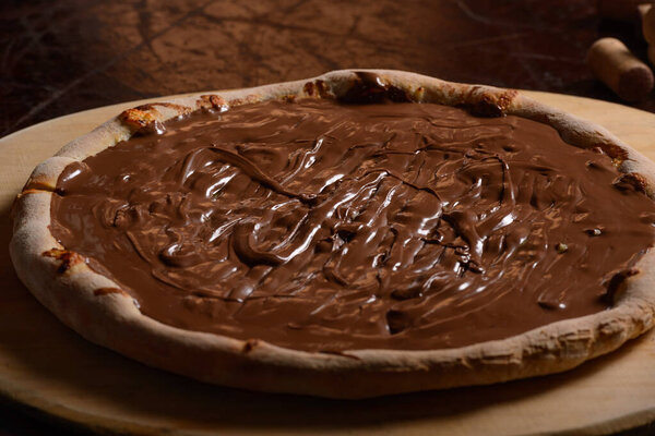 Chocolate pizza on wooden board. Brazilian sweet pizza.