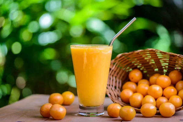 Brazilian fruit caja. Glass of juice on wooden table.