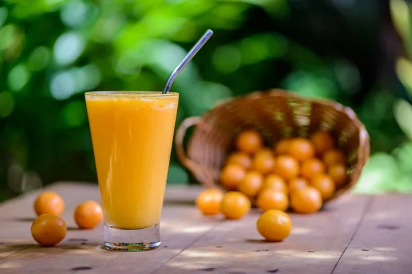 Brazilian fruit caja. Glass of juice on wooden table.