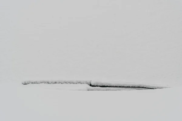 Snow covered windshield with wiper blades. Frozen snow on car in cold winter morning. Concept of driving in winter time with snow on road. Winter season. Copy space