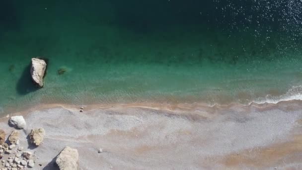 Letecký pohled shora na azurové moře a růžové oblázky pláže. Malé vlny na křišťálově čisté vodní hladině v pohybu rozmazané. Letní oceán moře pláž pozadí. Nikdo. Dovolená, dovolená a cestování koncept