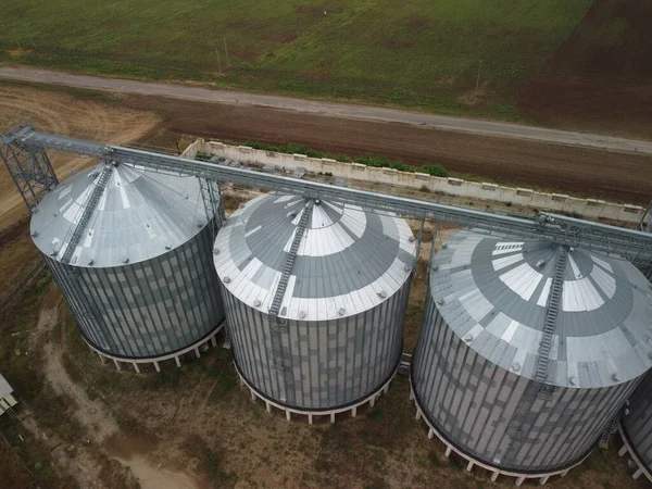 Grain elevator. Metal grain elevator in agricultural zone. Agriculture storage for harvest. Grain elevators on green nature background. Exterior of agricultural factory. Nobody.