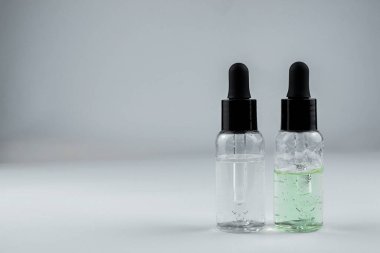 Hafif arka planda iki şişe kozmetik serumu.