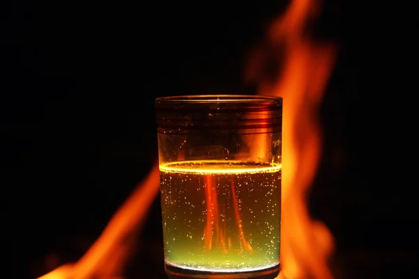 Verre d'eau gazeuse devant le feu — Photo