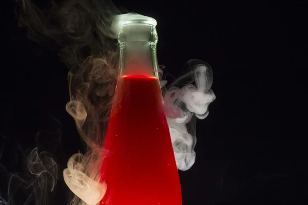 Bottle with red liquid surrounded with smoke Royalty Free Stock Photos