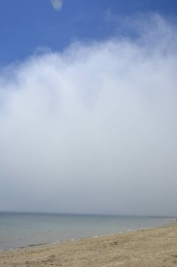 Beyaz bulut ile kaplı deniz kıyısı. Uçsuz bucaksız ufku olan kumsal..