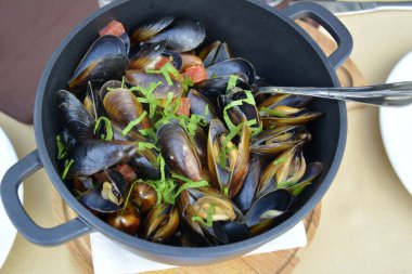 Şarap soslu deniz midyesi ve siyah tavada bir tutam yeşil soğan. Geleneksel yemek..