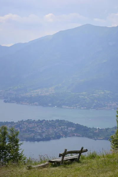 Banc en bois debout sur le bord de la colline avec vue lointaine sur le lac vertical — Photo