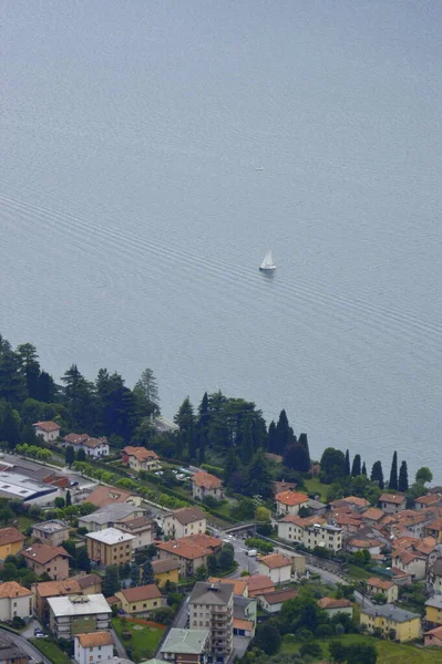 Kleine Boote schwimmen am Ufer eines kleinen Dorfes. Blick vom Hügel hinunter zum Comer See — Stockfoto