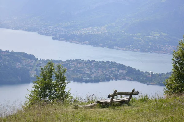 Banc en bois debout sur le bord de la colline avec vue lointaine sur le lac — Photo